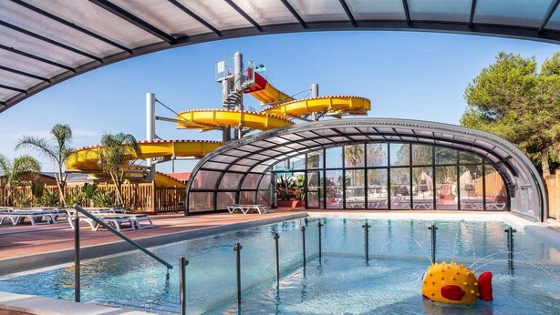 A swimming pool with a water slide and a sunshade structure.