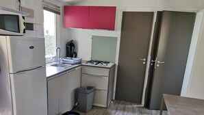 A compact kitchen with a refrigerator, microwave, sink, and stove.