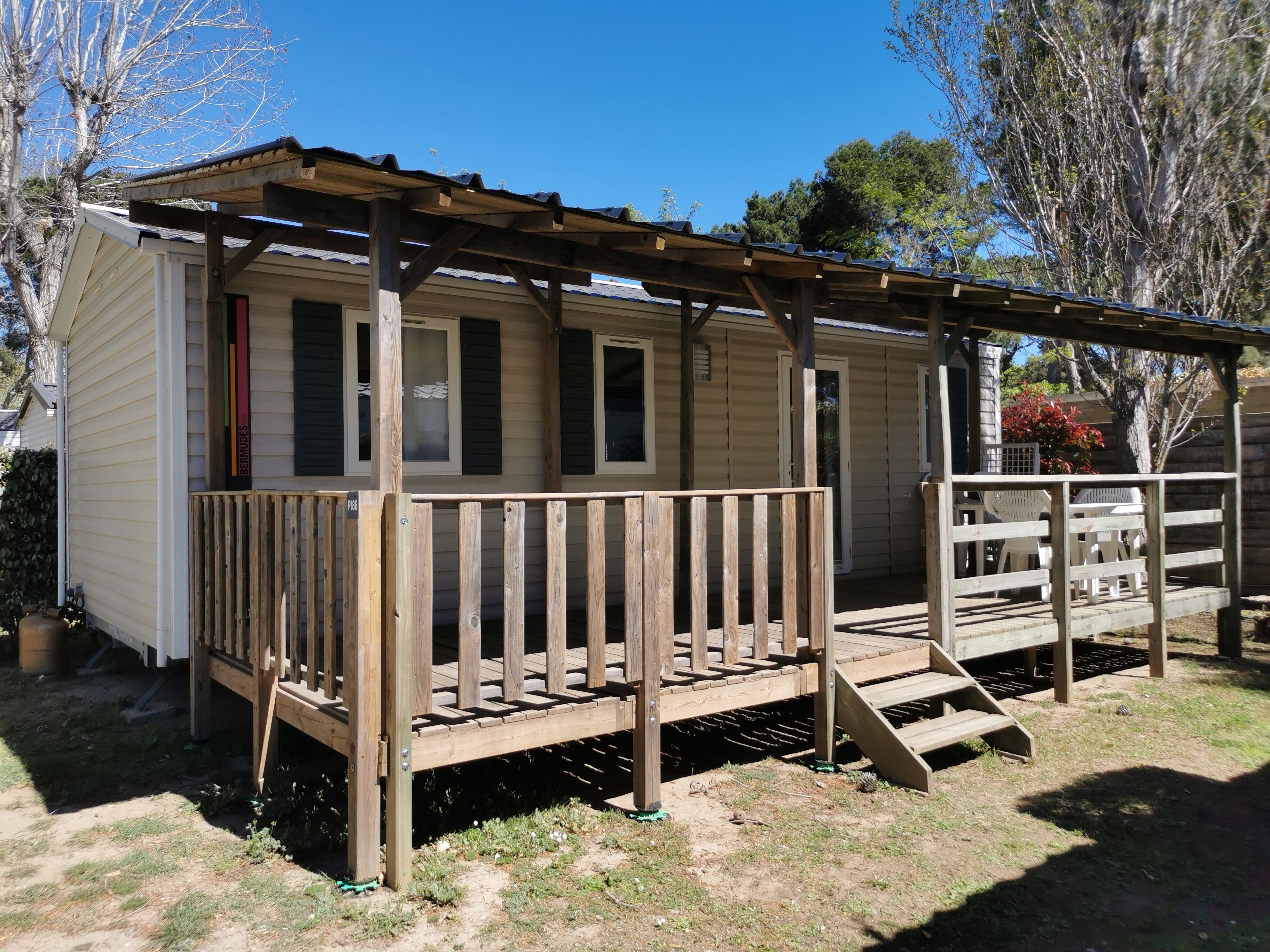A single-story mobile home with a wooden deck and a covered porch.
