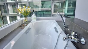A modern bathroom with a large bathtub, a glass shower enclosure, and a vase of flowers on the windowsill. - Bo504 - 1 Bdr Condo With Sea View, Ao Nang Beach (Krabi)