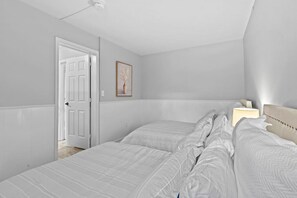 Ein Schlafzimmer mit zwei Betten, einem Nachttisch mit Lampe, einer Tür und einem gerahmten Bild an der Wand.