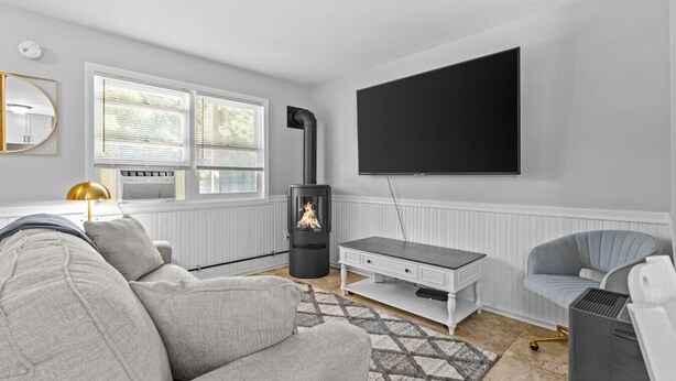 Un salon moderne avec un canapé, un téléviseur, une cheminée et un radiateur.