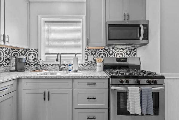 A kitchen with a microwave, stove, and sink.