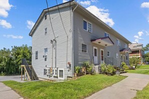 Ein zweistöckiges Haus mit Veranda, kleinem Garten und einer sichtbaren Treppe, die zum Eingang führt.