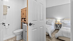 Une salle de bain avec des toilettes, un meuble en bois et une serviette accrochée au mur.