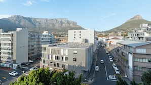 Un paisaje urbano con edificios modernos, cielo despejado y una montaña destacada al fondo.