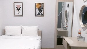 A hotel room with a bed, a desk, a mirror, and a washing machine. - DAIMA Syariah Mansion Tebet (Jakarta)