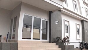 A modern two-story building with a flat facade, large windows, and a set of stairs leading to the entrance. - DAIMA Syariah Mansion Tebet (Jakarta)