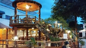 Une structure rustique en bois, dotée d’une plateforme circulaire, de bancs et d’une statue d’oiseau.
