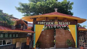 L’entrée du Fortview Resort se distingue par un portail en bois, des rideaux jaunes et verts, et une enseigne placée au-dessus.