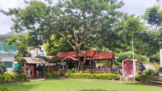 Un parc doté d’un pavillon à toit rouge, d’une pelouse verdoyante et d’une statue.