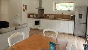 Una cocina moderna con armarios blancos, un refrigerador de acero inoxidable y un ventanal que proporciona luz natural.