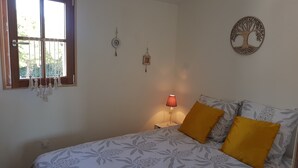 A bedroom with a bed, a window, and wall decorations. - Joli Petit Appartement Neuf, au Calme et à Proximité de la mer et des Commerces (La Guérinière)