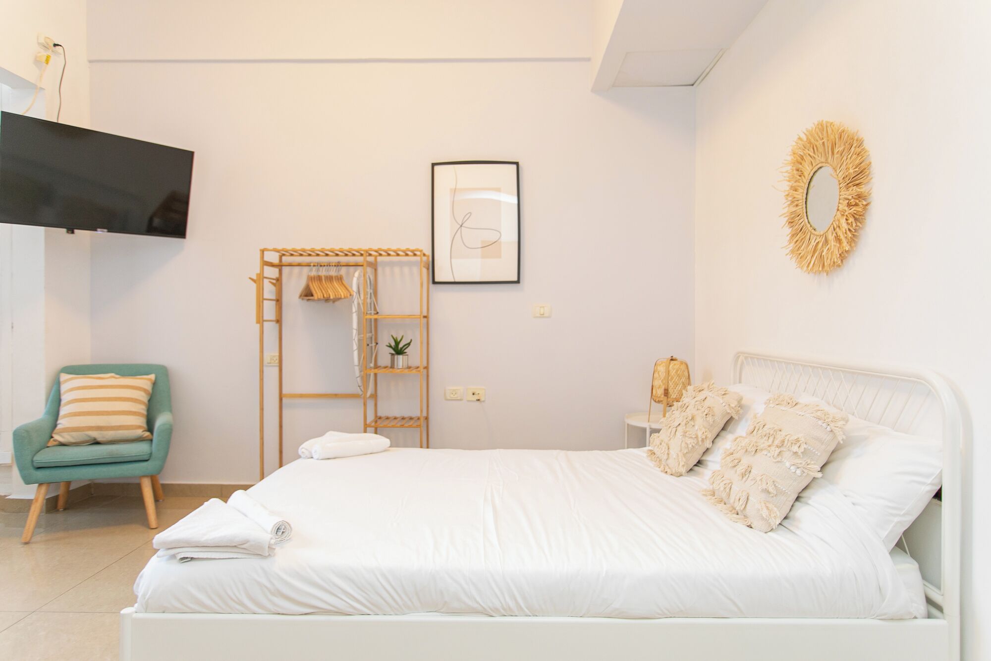 A bedroom with a bed, a chair, a TV, a shelf, and a wall decoration.
