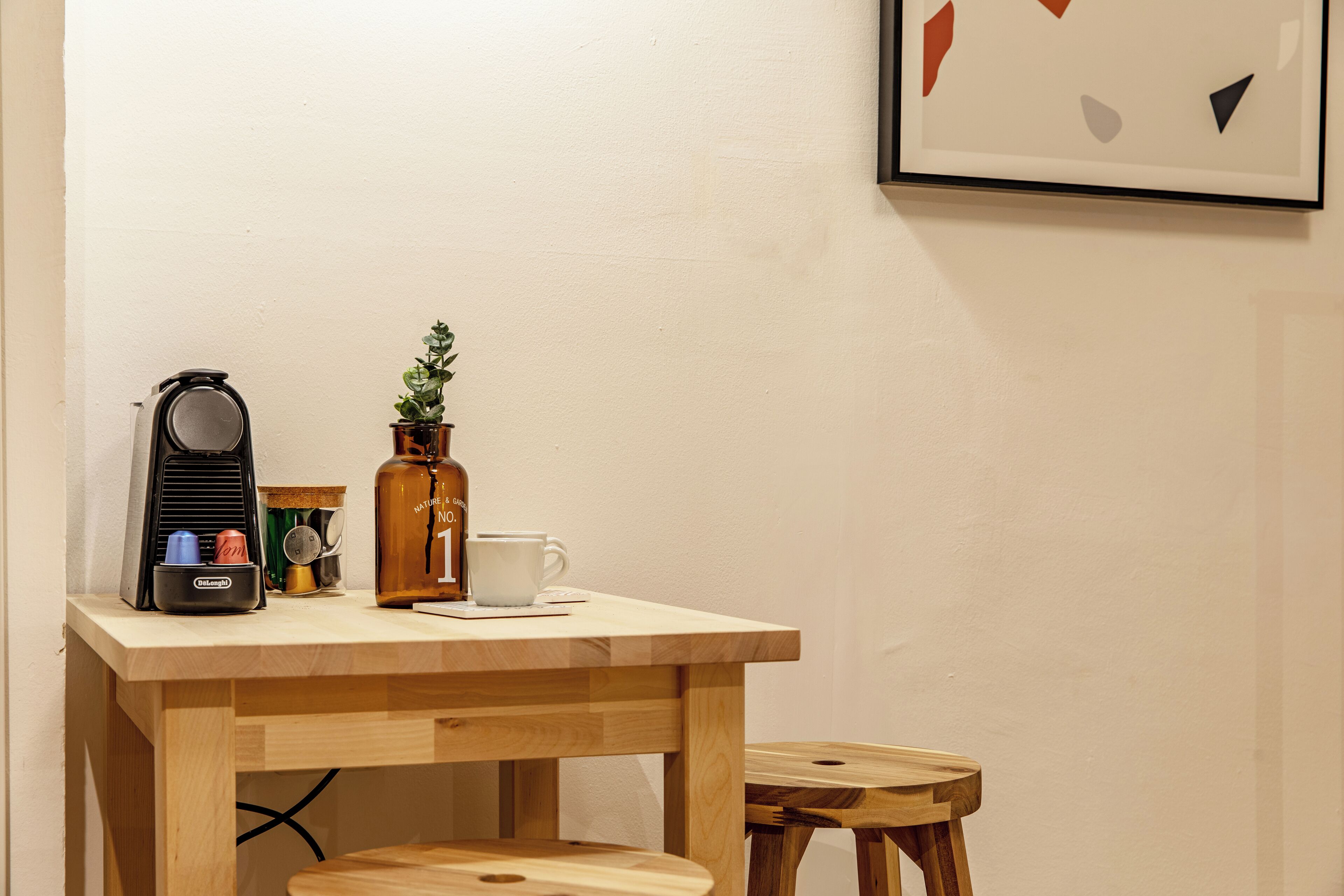 Une table en bois sur laquelle se trouvent une tasse blanche, une petite plante en pot, une radio ancienne et un thermos.