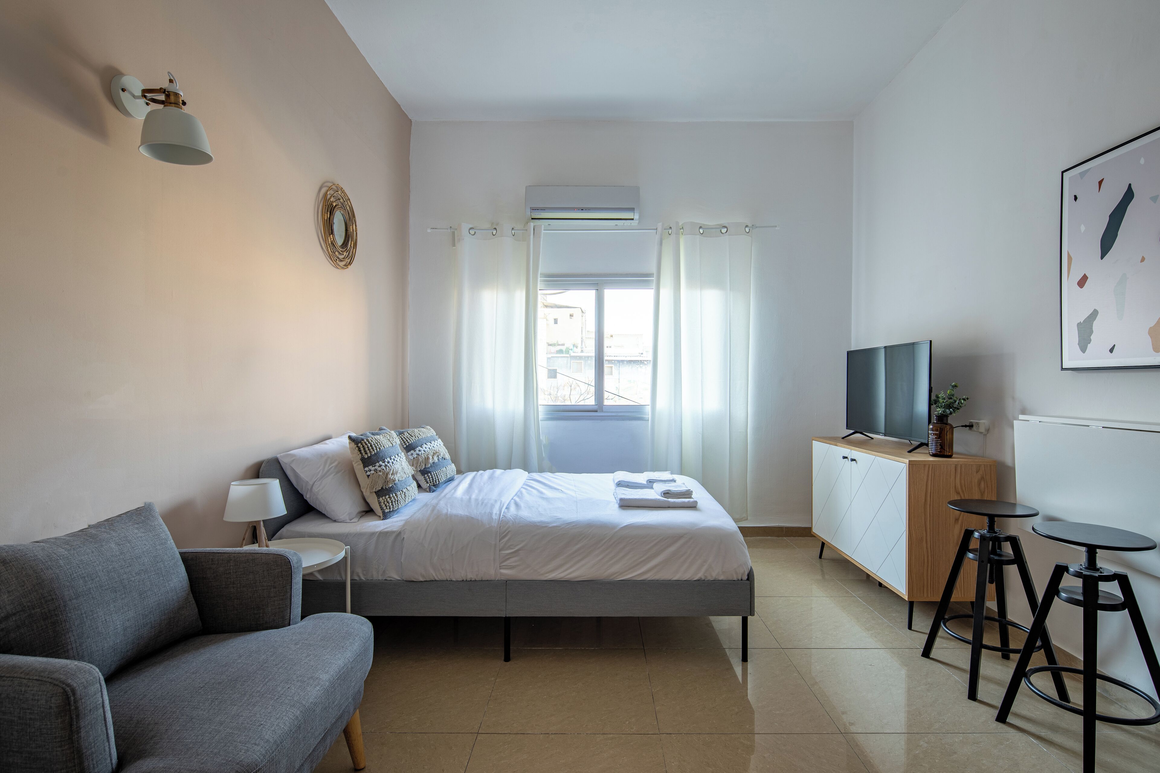 A modern bedroom with a bed, a sofa, a TV, and a desk.