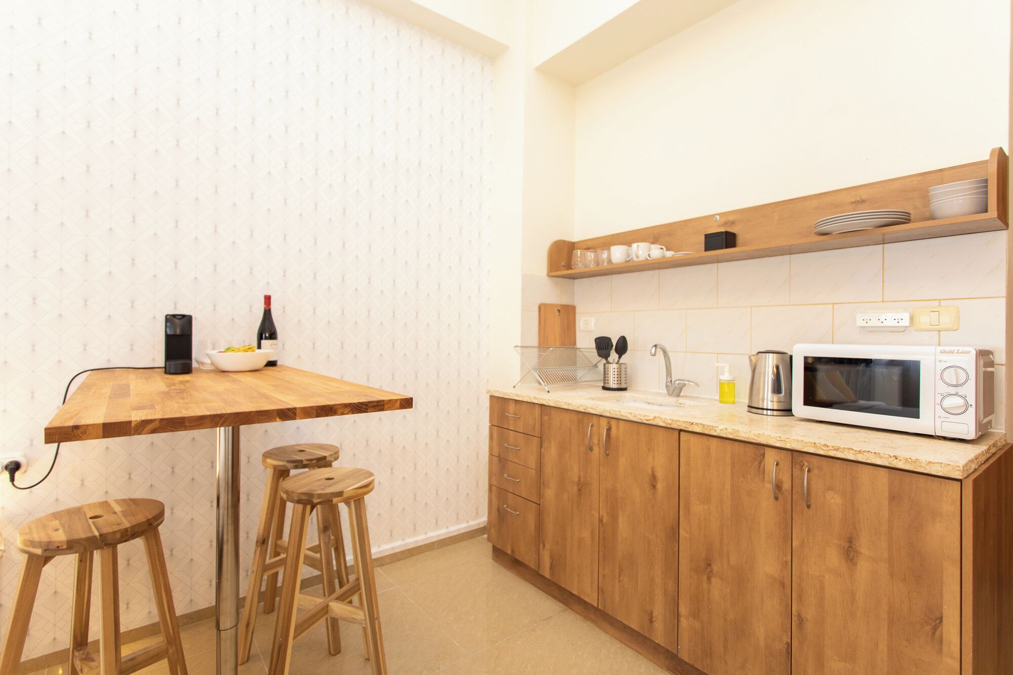 Une cuisine compacte avec des meubles en bois, un four à micro-ondes encastré et un petit plan de travail.