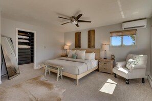A bedroom with a bed, bedside tables, a chair, a ceiling fan, an air conditioning unit, a window, and a closet. - @ Marbella Lane - Eccentric 4BR Modern Ranch Home (Reno)