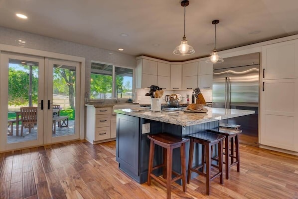 A modern kitchen with a large island, stainless steel appliances, and a view to the outdoors.