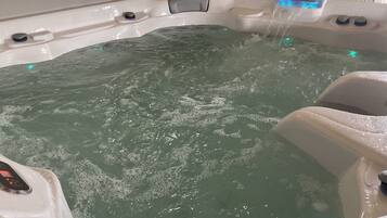 Ein Whirlpool mit Wasserdüsen, einer Bedienkonsole und einer Sitzgelegenheit.