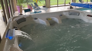 Un jacuzzi con agua fluyendo, rodeado de sillones de descanso y plantas en macetas.