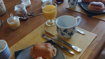 Een ontbijttafel met croissants, sinaasappelsap en diverse toevoegingen.