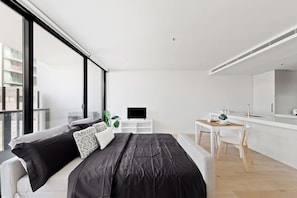 Ein modernes Schlafzimmer mit Bett, Schreibtisch und Fernseher.