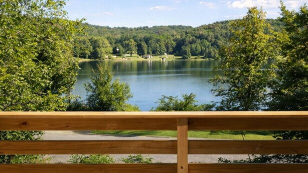 A hot tub with a lake view, surrounded by trees and a wooden deck. - Lakefront in Logan (In the heart of Hocking Hills) (Logan)