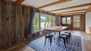 A room with a wooden ceiling, large windows, a wooden table with chairs, and a patterned rug. - Lakefront in Logan (In the heart of Hocking Hills) (Logan)