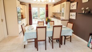 Een eethoek met een tafel voor vier personen, omringd door stoelen, en een keuken op de achtergrond.