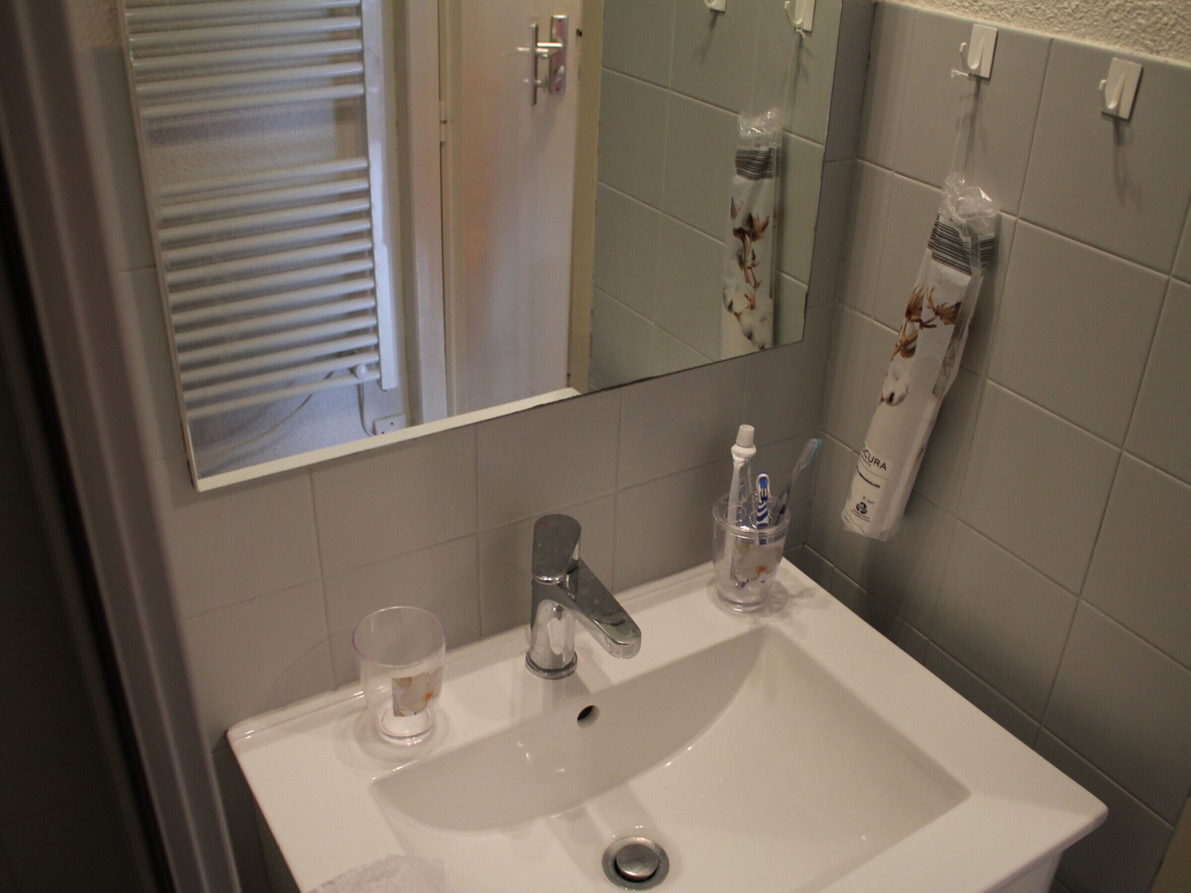 A bathroom with a white sink, a mirror, and a toilet.