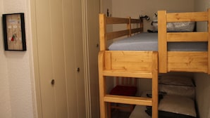 A small, compact room with a bunk bed, a wooden door, and a wall-mounted key rack. - Studio for 4, balcony, shared parking (Valloire)