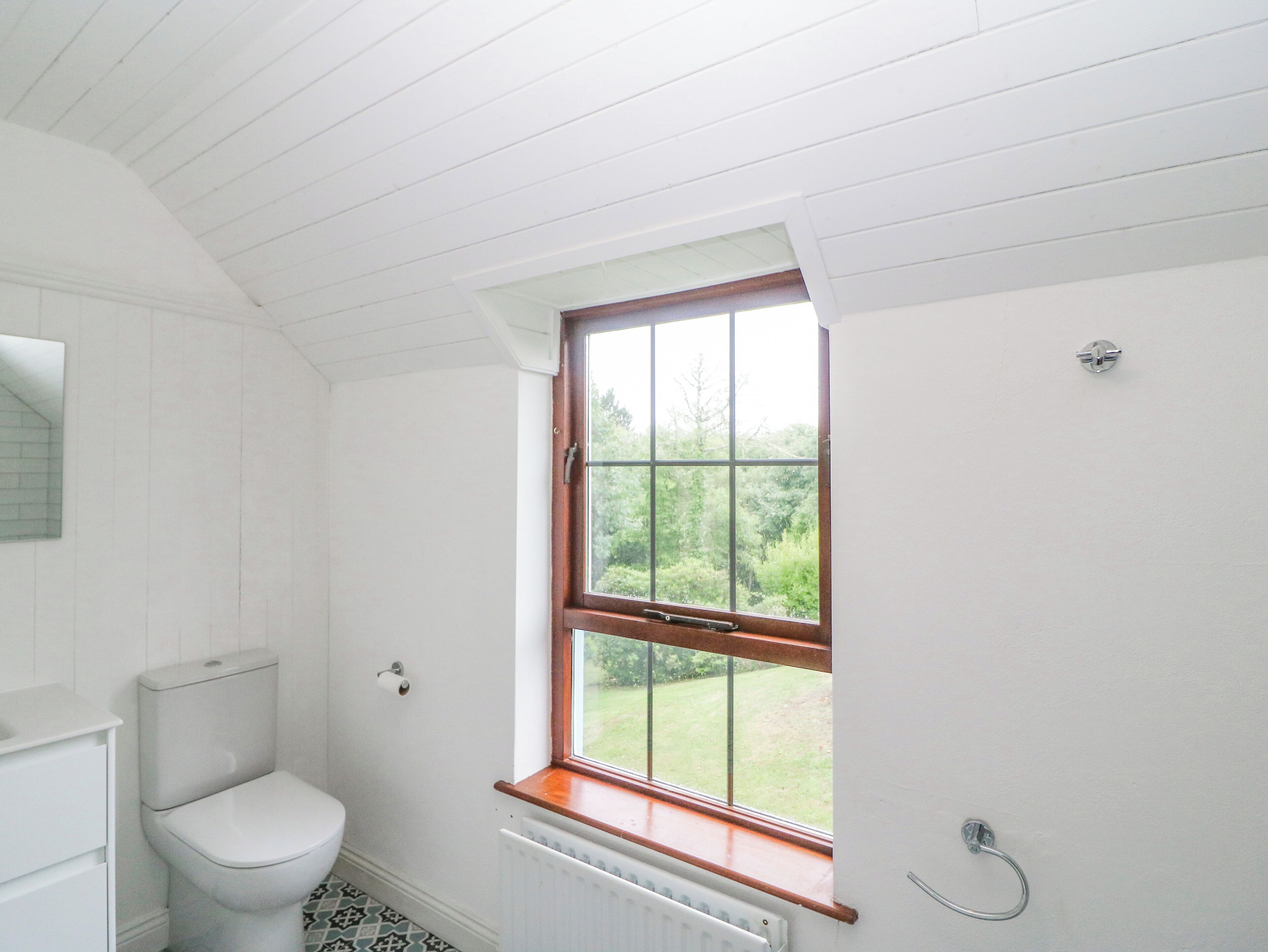 A bathroom with a toilet, a window, and a radiator.