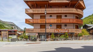 En bygning med flere etager, altaner, et restaurantskilt og et bjerg i baggrunden.