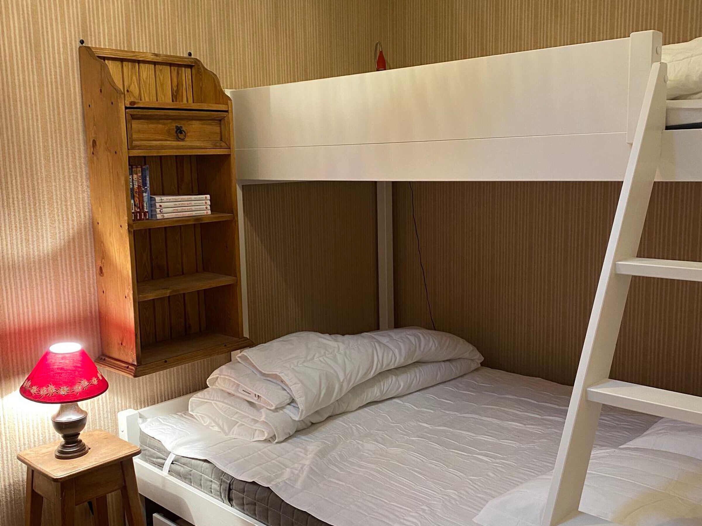 Una cama litera con cabecera de madera y repisa superior.