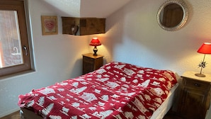 A bedroom with a bed, two bedside tables, a window, and a mirror on the wall.