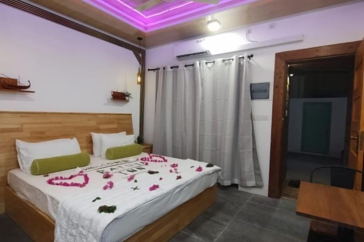Une chambre à coucher avec un lit en bois, une table de chevet, un rideau et une porte.