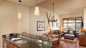 A kitchen with granite countertops, a built-in sink, and a dining area with a wooden table and chairs. - Glacier Cove | Capitol Peak Lodge #3125 | 1B/1B (Snowmass Village)