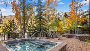 A hot tub surrounded by a brick patio, with a pool in the background and autumn foliage. - Glacier Cove | Capitol Peak Lodge #3125 | 1B/1B (Snowmass Village)