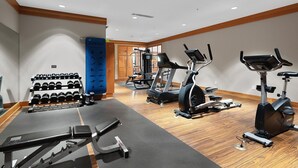 Een sportschool met loopbanden, elliptische trainers en een rek met dumbbells.