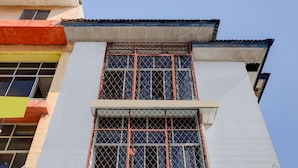 Ein mehrstöckiges Gebäude mit weißer Fassade, einem rot-gelben unteren Bereich und einem blauen Dach.