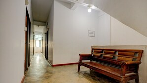Ein Korridor mit einer Holzbänklä, einer Treppe und einer Tür zu einem anderen Raum.