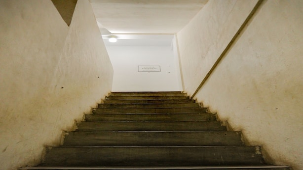 Eine Treppe führt zu einer Tür, über der ein Schild hängt.