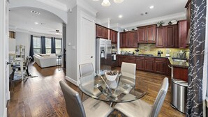 A modern kitchen with wooden cabinets, stainless steel appliances, and a glass dining table. - Near Heights, DT, Montrose, Washington | BBQ WiFi (Houston)