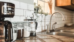 A kitchen with a coffee maker, jars, and a sink.