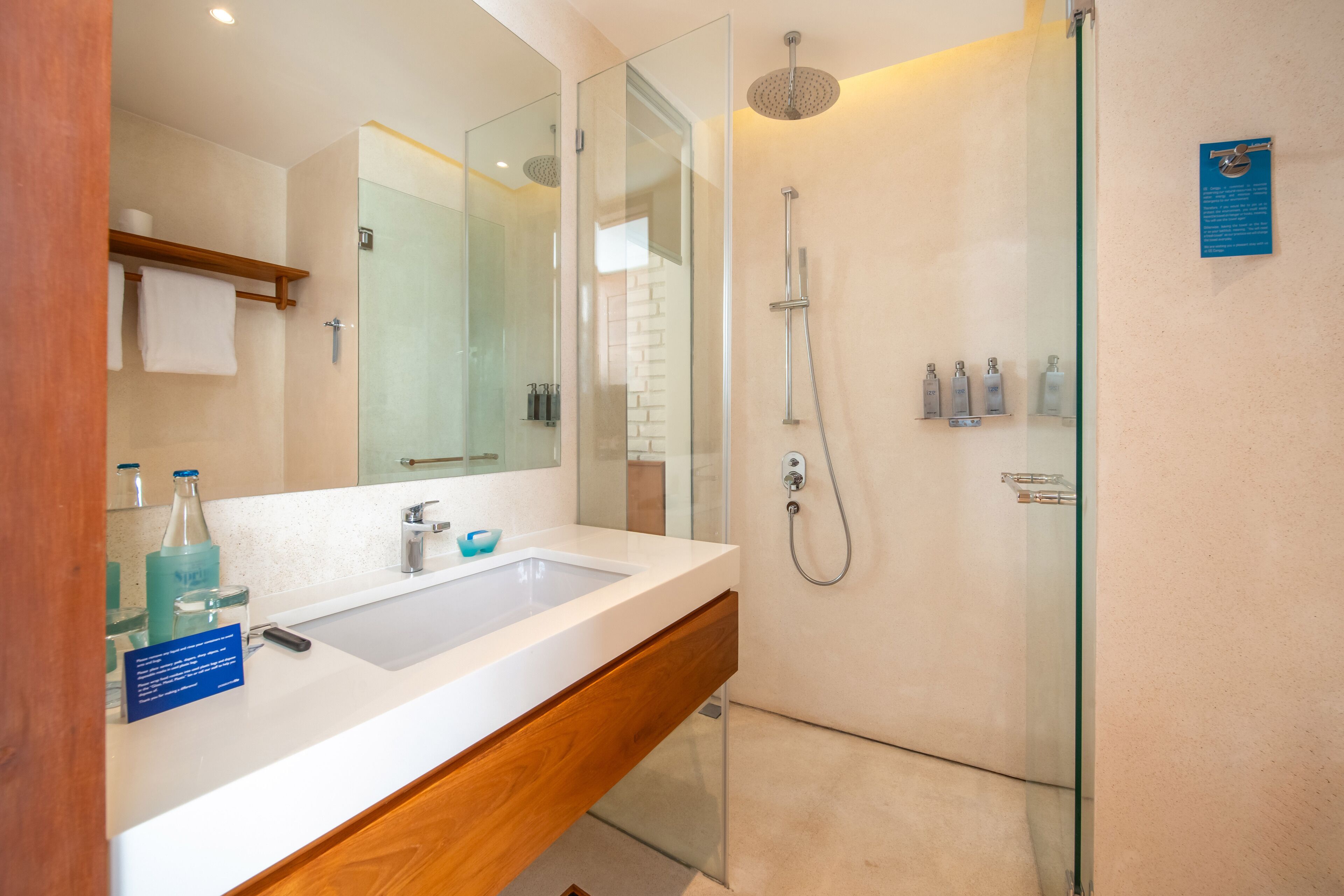A modern bathroom with a glass-enclosed shower, a large mirror, and a white sink.