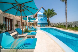 Una piscina al aire libre, sombrillas, sillones reclinables de piscina