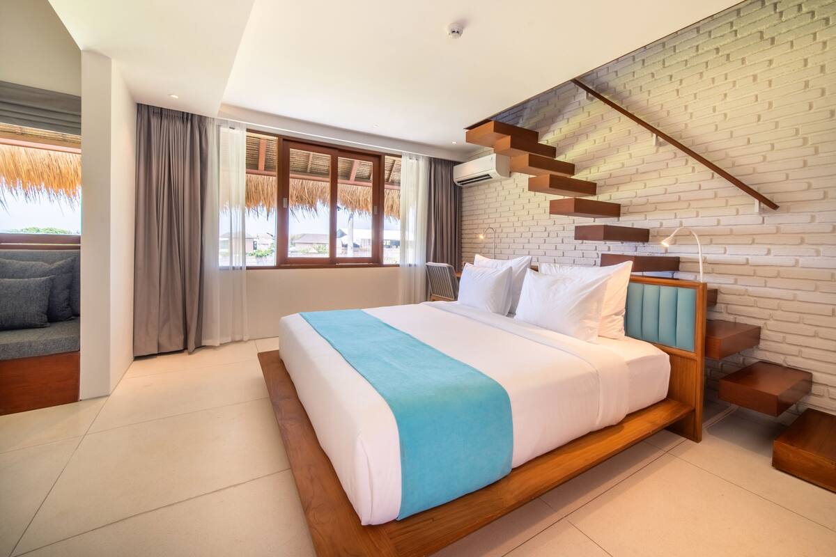 Un dormitorio moderno con una cama grande, una escalera y vistas al exterior.