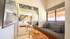 Quarto de hotel moderno com cama, sofá, mesa de madeira e uma janela grande com vista.