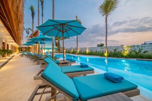 Una piscina al aire libre, sombrillas, sillones reclinables de piscina